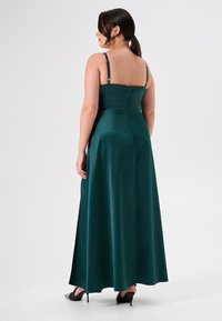 Langes, dunkelgrünes Satin-Kleid mit verstellbaren Spaghettiträgern, tailliertem Oberteil und fließendem Rock. Reißverschluss auf der Rückseite und glatte Textur.