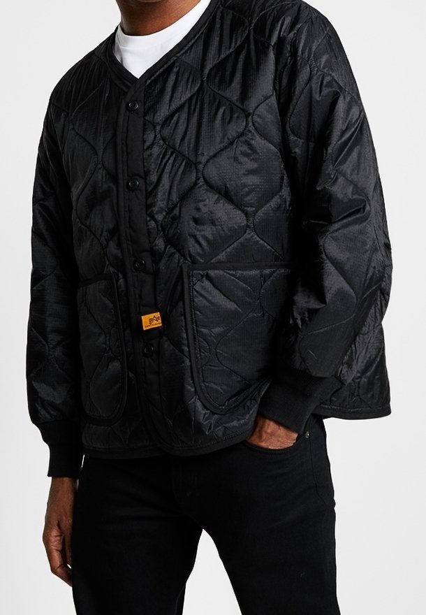 Sort quiltet jakke med knaplukning foran, ribstrikkede manchetter og to forlommer. Fremtrædende tekstur med diamantmønster og mærketag.