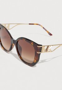 Γυαλιά ηλίου με καφέ φακούς με διαβάθμιση και μεταλλικά χρυσά μπράτσα με διάτρητο λογότυπο "MK".