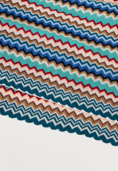 Πολύχρωμο πλεκτό ύφασμα με επαναλαμβανόμενες ζιγκ ζαγκ ρίγες σε αποχρώσεις μπλε, τιρκουάζ, κόκκινο, λευκό, καφέ και μπεζ.
