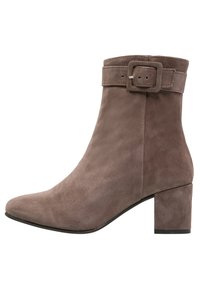 Bottine en daim taupe, avec un bout carré, un talon bloc effilé et une large sangle avec une boucle rectangulaire.