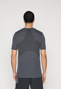 Αθλητικό πουκάμισο με κοντά μανίκια, σκούρο γκρι, με υφασμάτινο μοτίβο, εφαρμοστή γραμμή και λογότυπο στην πλάτη κάτω από τη γραμμή του λαιμού.