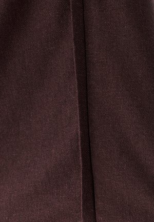 Dark brown textured fabric showing a close-up of the weave and a prominent vertical seam. The material appears soft and dense.