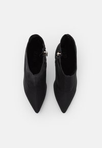 Sorte spidse ankelstøvler med en glat læderlignende overflade, der har en sidedragt og et minimalistisk design.