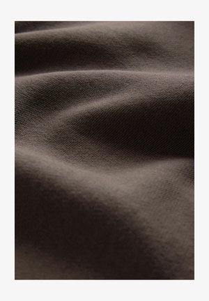 Hnedá textília s jemne štruktúrovaným povrchom, vykazujúca jemné záhyby a hladký vzhľad, zdôrazňujúca svoju flexibilitu a padavé vlastnosti.