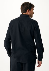 Zwarte heren langemouwenshirt, gemaakt van ademend materiaal, met een overhemdkraag, manchet-sleeves en een afgeronde onderkant.