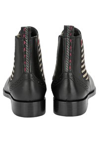 Bottines en cuir noir avec des côtés en tissu rayé, des coutures contrastées et un talon bloc solide. Détails de brogue remarquables à l'arrière.
