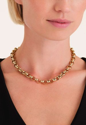 Collar de cadena de oro con eslabones ovalados interconectados, acabado liso, llevado alrededor del cuello, combinado con una blusa negra, vista cercana.