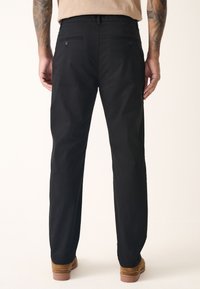 Black cotton pants with a straight leg design, featuring two back pockets, subtle texture, and a classic waistband.