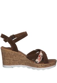 Brown suede wedge sandals with crisscross straps, floral fabric accent, textured cork base, and white rubber sole. Elegant and modern design.