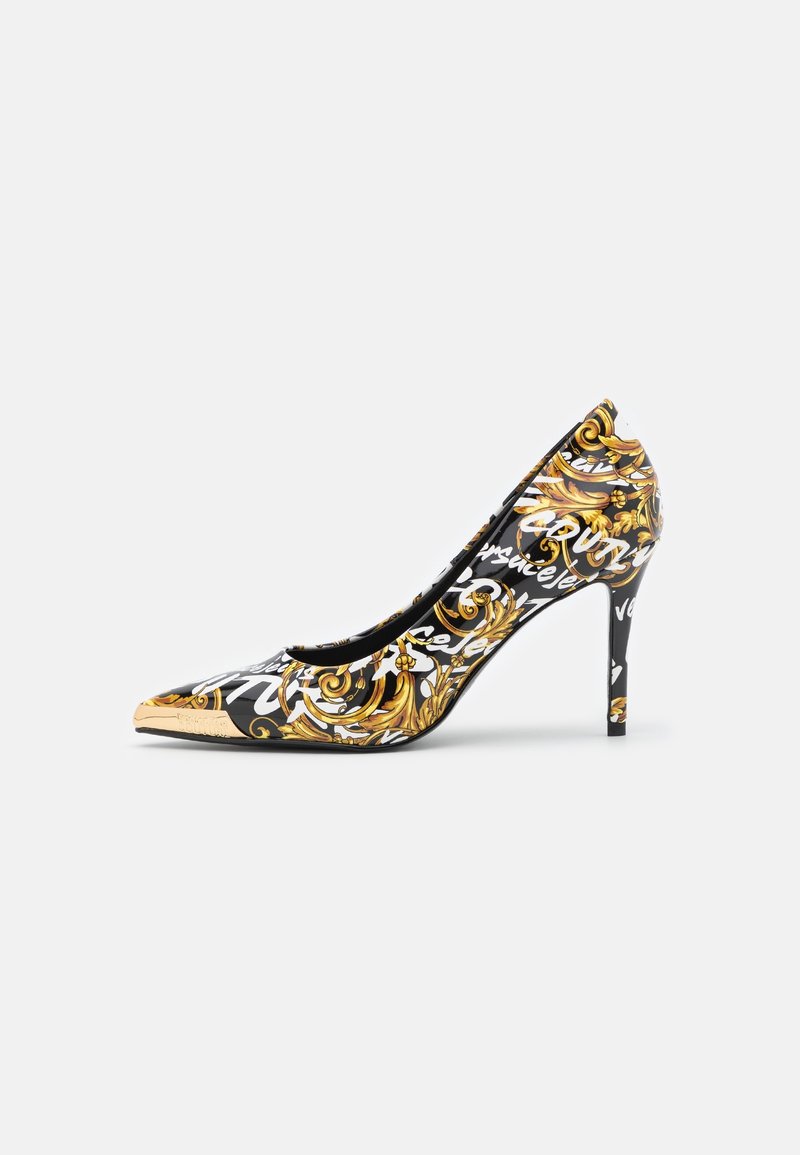 Chaussure à talon haut pointue noire avec des motifs baroques dorés et une écriture manuscrite blanche sur fond blanc.