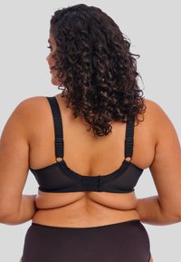 Sutiã preto com tecido suave, alças ajustáveis e fecho de gancho e laço. Apresenta uma faixa larga e bordas suaves para conforto.