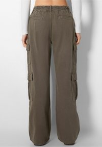 Pantalones cargo holgados de tejido verde oliva, que cuentan con múltiples bolsillos laterales, una cinturilla elástica y un diseño de pierna recta.