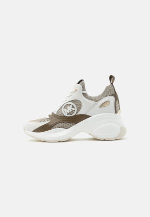 Chaussure de sport épaisse avec semelle blanche, tige en tissu tricoté beige et marron, surcouches en cuir blanc et emblème rond avec logo sur le côté.
