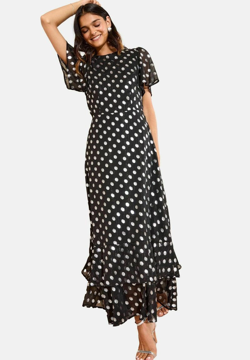 Schwarz gepunktetes Maxikleid aus transparenter Stoff mit silbernen Punkten, ausgestelltem Saum und kurzen Ärmeln. Mit geschichteten Rüschen am Saum.