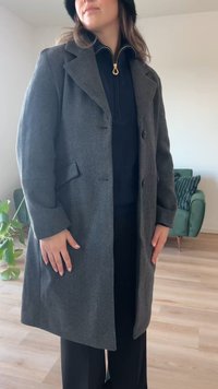 Manteau en mélange de laine gris au design cintré, avec un col cranté et deux boutons. Poches situées sur les côtés.