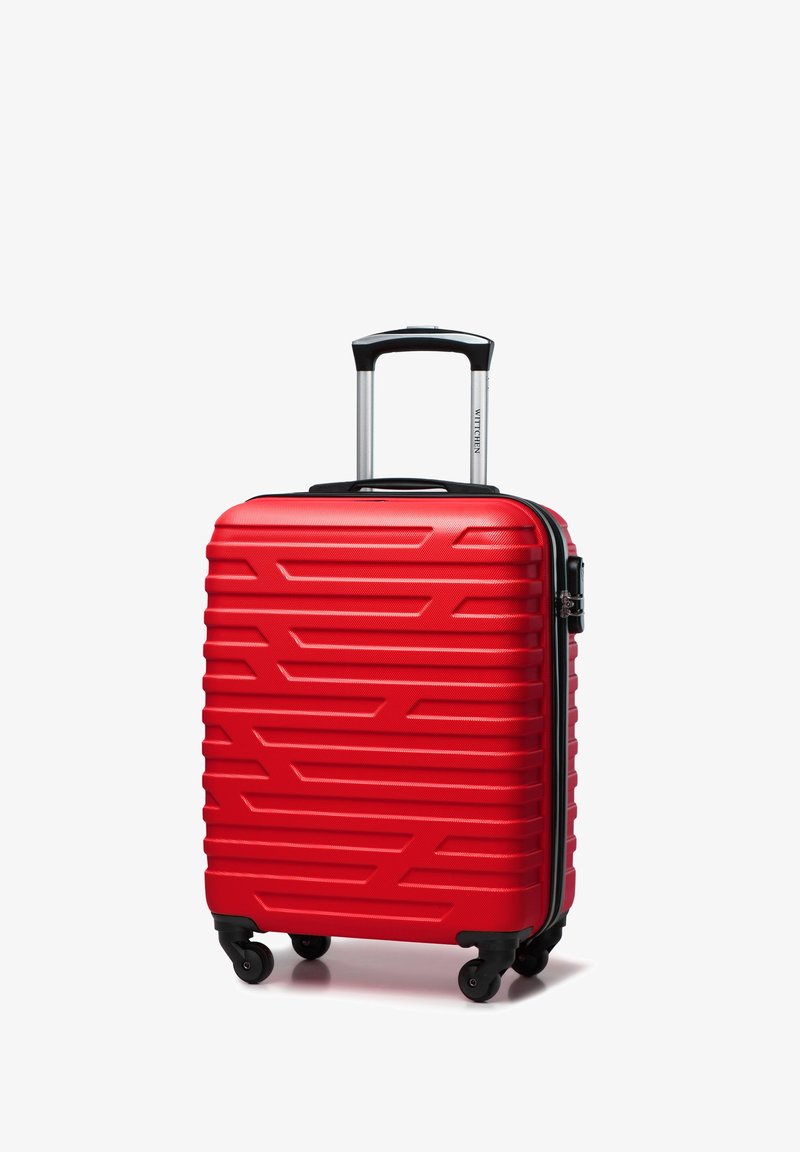 Valise rigide rouge avec un motif en zigzag texturé, une poignée extensible argentée et quatre roues noires pour la mobilité.