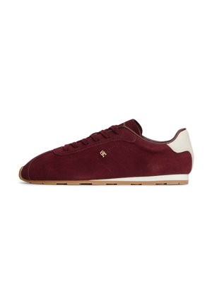 Niskoprofilowy bordowy zamszowy sneaker z białym obcasem i gumową podeszwą, z sznurowadłami i małym złotym logo po boku.