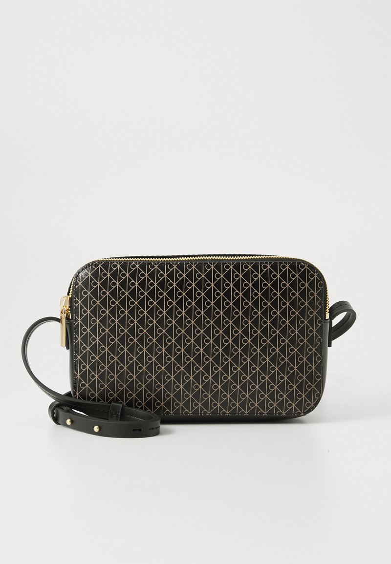 Geantă neagră rectangulară tip crossbody cu un model geometric auriu, fermoar auriu și curea neagră ajustabilă, așezată pe un fundal alb.