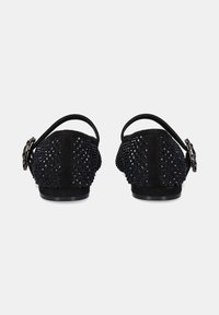 Zapatos de talón descubierto en negro con una parte superior de malla texturizada adornada con pequeños embellishments negros, un tacón de ante suave y un detalle de hebilla plateada.