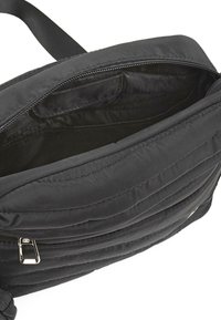 Bolso bandolera negro acolchado con cremallera abierta, que muestra un interior espacioso con varios bolsillos pequeños y un forro de tela.