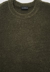 Olivgrüner Pullover aus strukturiertem, flauschigem Material mit Rundhalsausschnitt und einem Etikett mit der Aufschrift "CALLIOPE" auf der Innenseite.