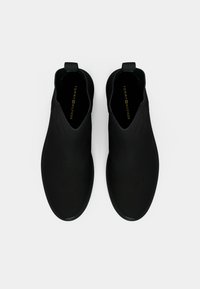 Stivali Chelsea neri con un design elegante, materiale sintetico liscio, linguetta per indossarli, e logo sulla soletta, con una forma della punta arrotondata.