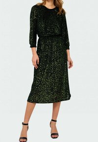 Robe noire midi avec imprimé léopard vert, encolure ronde, manches trois quarts, taille élastique et tissu fluide et texturé.