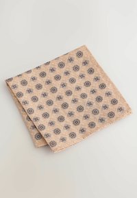 Patterned cloth napkin in light brown with floral motifs in dark brown and white. Soft texture, folded neatly, featuring a geometric design.