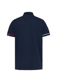 Polo navy con cuello clásico, de manga corta con acentos en rojo y blanco en los puños, hecho de material de algodón suave.