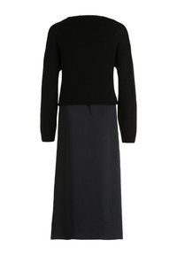 Pull noir à manches longues en maille courte associé à une jupe noire taille haute longueur cheville, vue de dos.