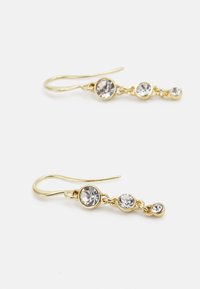 Pendientes colgantes en tono dorado que presentan tres rhinestones transparentes de diferentes tamaños, conectados por delicados acentos de cadena metálica.