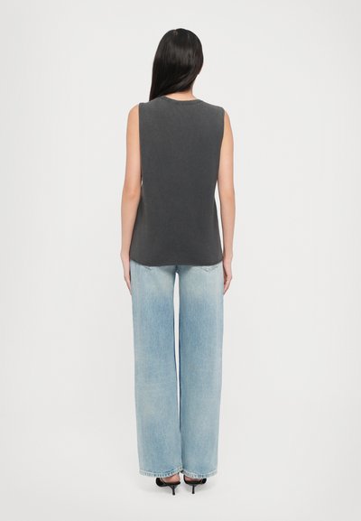 Grå ermeløs topp med en avslappet passform, sammen med lyseblå vide jeans. Glatt stoff med minimalt design og ingen synlige mønstre.