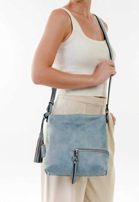 Borsa crossbody in pelle di un blu chiaro con una texture liscia, tasca con zip, tracolla regolabile e accenti scuri a contrasto.