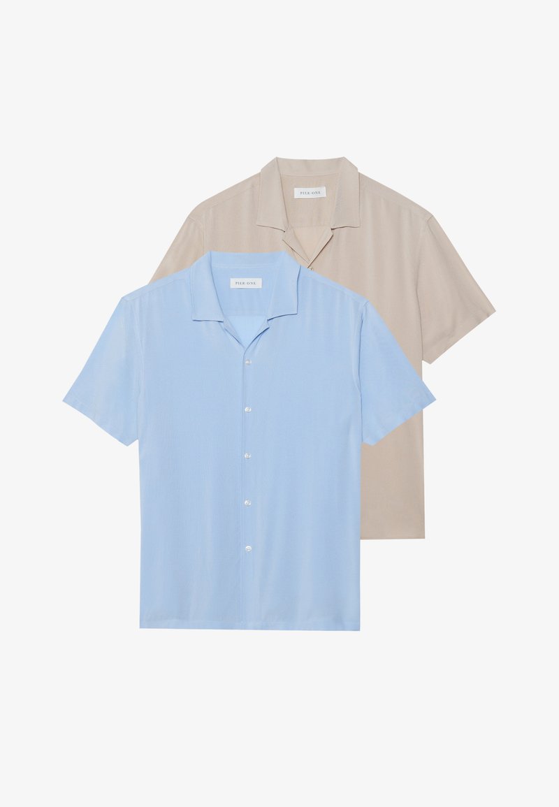 Sono esposte due camicie a maniche corte; una di colore azzurro chiaro e l'altra beige. Entrambe presentano un design con colletto e apertura con bottoni, con una texture liscia.