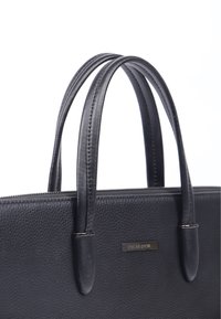 Sort læderhåndtaske med en pebble-lignende tekstur, dobbelte håndtag og lynlås-lukning. Udstyret med en metal mærkeskilt med teksten "CYCAS D'OR."