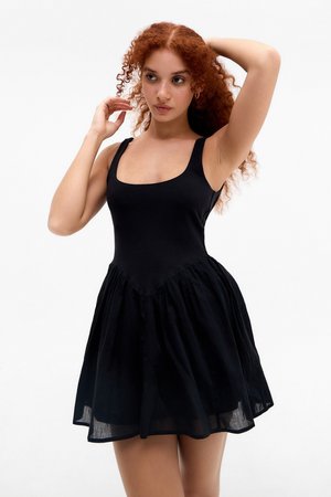 Schwarzes Kleid mit tailliertem Oberteil und schwingendem Rock, aus weichem Stoff. Es hat breite Träger und einen quadratischen Ausschnitt.