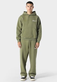 Oliivinvihreä huppari ja siihen sopivat verkkarit, jotka on valmistettu pehmeästä kankaasta. Hupparissa on etutasku ja logoyksityiskohta rinnassa ja lahkeessa.