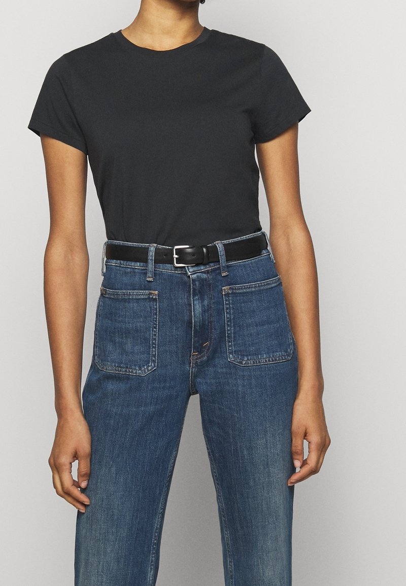 T-shirt en coton noir à manches courtes, associé à un jean en denim bleu avec une ceinture noire, mettant en avant deux poches arrière et une coupe classique.