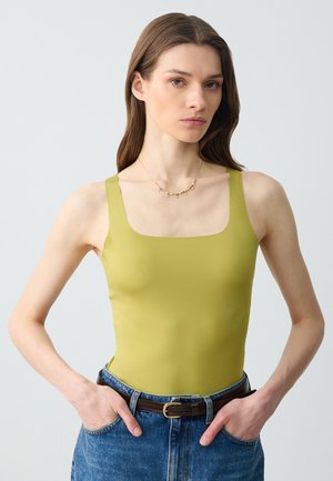 Olive green bodysuit with a square neckline and wide straps, paired with high-waisted blue jeans and a brown belt. Smooth, fitted texture.