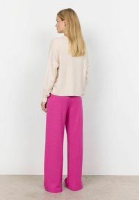 Beige long-sleeve top with a loose fit, paired with bright pink wide-leg pants, both made from soft fabric. Simple design, no visible patterns.