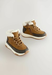 Braune und graue Knöchelstiefel mit einem Futter aus Kunstfell, Schnürung vorne, Seitenreißverschluss und einer gepolsterten weißen Sohle mit beigen Akzenten.