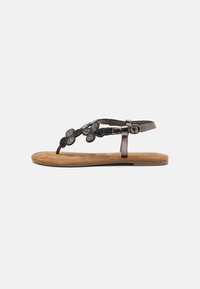 Flat thong sandal with a brown suede footbed, metallic strap featuring black textured flowers, and a buckle closure for adjustable fit.