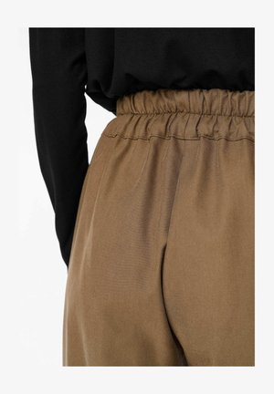 Brown elastic-waist trousers with a smooth texture and subtle pinstripes, paired with a fitted black long-sleeve top.