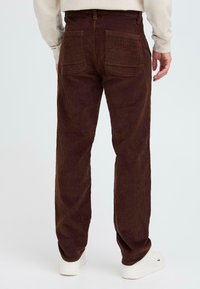 Brown corduroy pants with a straight leg design, featuring two rear pockets and visible texture from the ribbed fabric.