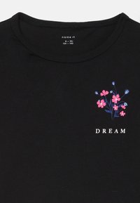 Schwarzes Baumwoll-T-Shirt mit einem floralen Design in Pink und Blau auf der linken Brust, mit dem Wort "DREAM" in Weiß darunter.