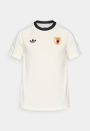 Cremefarbenes kurzärmeliges T-Shirt mit schwarzem Rippkragen, mehrfarbigen Streifen an den Ärmeln, einem Adidas-Logo und einem gestickten Emblem.