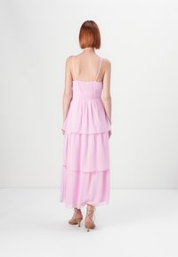 Lagdelt, ærmeløs maxikjole i lyserød med en smocket bodice, der har et prikmønster og delikate spaghetti-stropper.