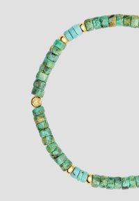 Turquoise beaded necklace with textured green beads and smooth gold accents, featuring a round gold pendant between larger turquoise pieces.