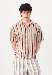 Cămașă cu mâneci scurte, cu nasturi, de culoare bej, cu dungi roșii și vișinii, având un material tricotat texturat și un design clasic al gulerului.
